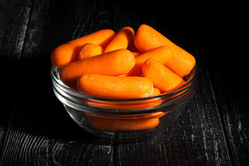 baby carrots on black wood background