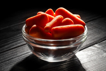 baby carrots on black wood background