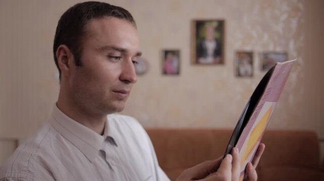 Man Examines A Vinyl Record With Interest 
