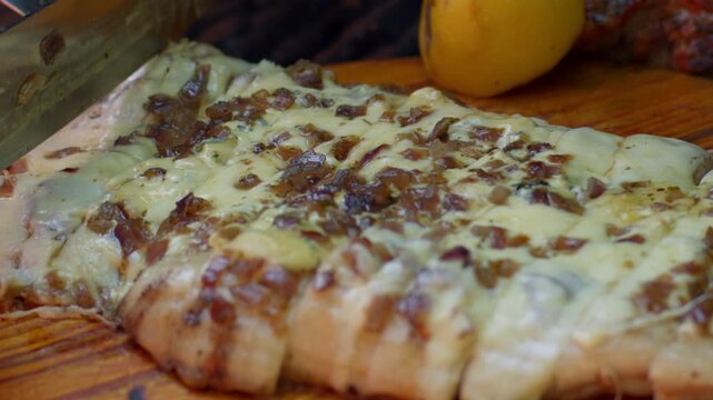 Slicing a Juicy pork with melt cheese and onion in a barbecue asado