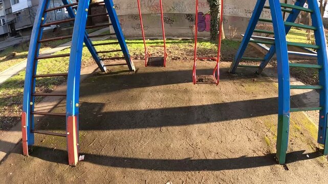 The metal swingset features two wooden seats painted in bright blue and red