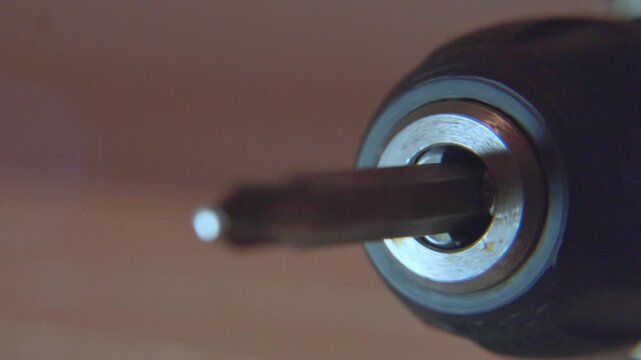 macro close up of metal crosshead phillips screwdriver bit spinning in slow motion against blurred neutral background showing industrial precision and metallic texture of rotating tool