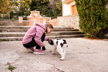 Teenage blonde Slavic girl pulling the leash of a resisting Russian spaniel dog on a concrete path in Montenegro