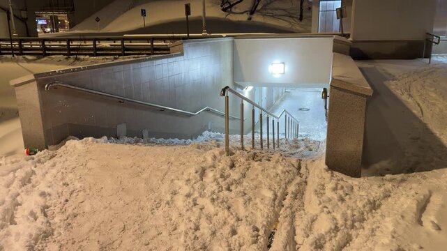 Snow covered stairs leading to urban underpass during heavy winter snowfall, difficult pedestrian access and seasonal city infrastructure problem in cold weather
