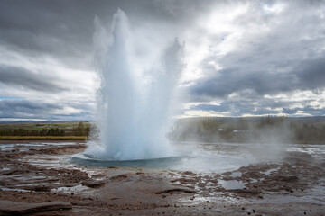 Powerful Geyser Eruption Shooting Water and Steam into the Air in a Rugged Geothermal Landscape of Iceland