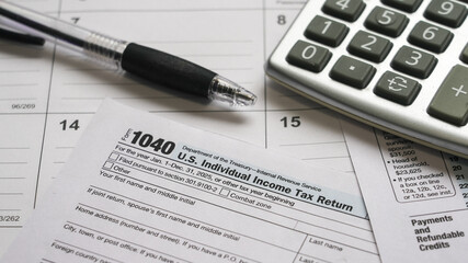 Filing an individual income tax return with a calculator, pen, and blank form 1040 document, representing tax season tasks