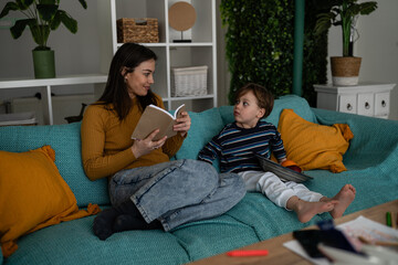 Fototapeta premium Mother reading book to young son at home