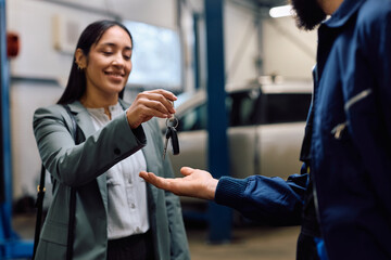 Close up of customer handing over her cay key to mechanic in workshop.