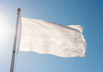 A white flag flying high on a flagpole against a clear blue sky with the sun shining brightly