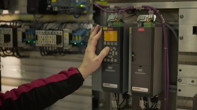 Electrical engineer inspecting industrial control cabinet and circuit breakers at factory