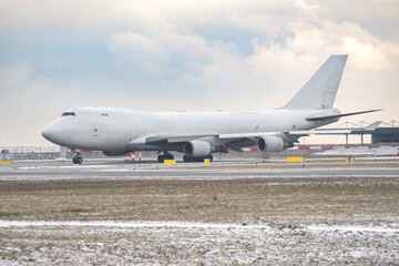 Generic unbranded white jumbo jet airplane taxiing on snowy airport runway in winter