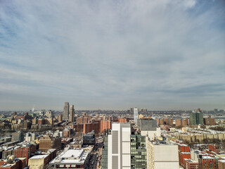 Naklejka premium Capturing a vast aerial perspective of new york city's diverse architecture and urban sprawl under a cloudy winter sky, showing buildings with rooftops lightly covered in snow