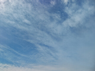 Fototapeta premium Blue sky with light, scattered cirrus and cirrocumulus clouds spreading across the frame, offering ample copy space and a serene, open natural environment background