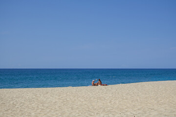Obraz premium Two people relaxing on sandy beach by the sea