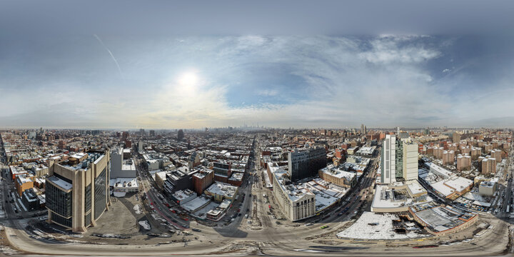 Expansive equirectangular panorama capturing manhattan's urban landscape in winter, showing city streets, buildings, and a distant skyline under a bright, cloudy sky in new york
