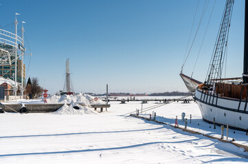 Fototapeta premium Frozen toronto harbour with snow covered piers and a schooner locked in ice, a crisp, serene winter day beneath a clear blue sky, calm waterfront and empty docks
