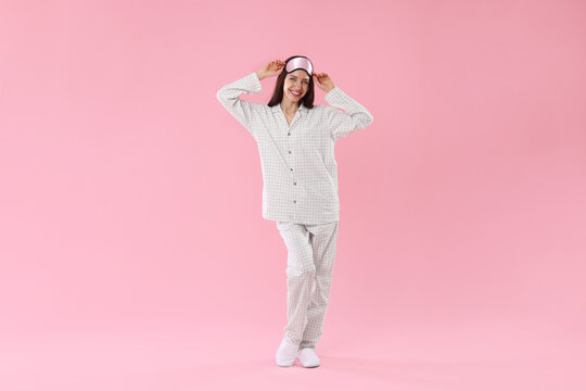 Beautiful woman wearing sleeping mask and stylish pajamas on pink background