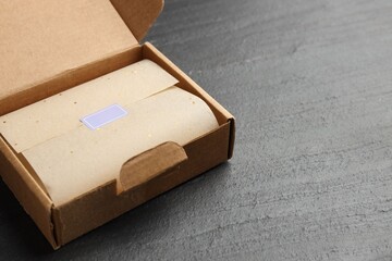 Cardboard box with packaging and blank sticker on black table, closeup. Space for text