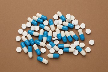 Many pills on brown background, flat lay