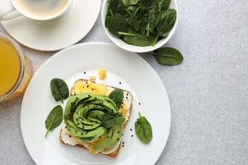 Tasty breakfast with avocado toast served on light grey table, flat lay. Space for text