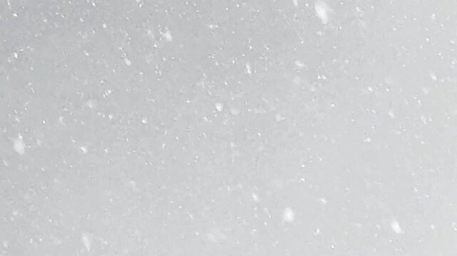 Heavy snowfall with thick snow falling outdoors. Winter weather with large snowflakes filling the air, creating a blurry bokeh effect and cozy dramatic mood.