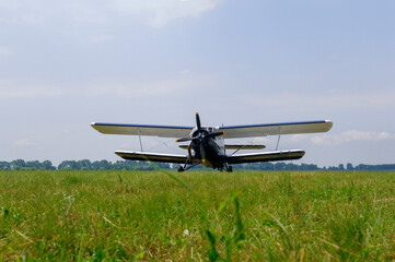 Single propeller airplane parked on grassy field under blue sky