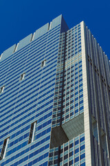 Obraz premium Modern office building rises against clear blue sky in a busy urban area during daytime hours