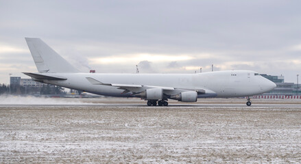 Side profile of a generic white jumbo jet airplane taxiing on a snowy airport runway