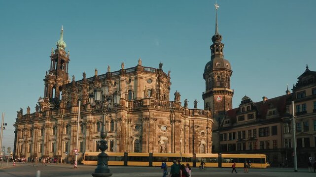 a still shot of a yellow tram drive through the square in front of Dresden Cathedral or Cathedral of the Holy Trinity, Dresden,previously the Catholic Church of the Royal Court of Saxony