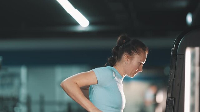 Strong athletic woman training triceps on parallel bars in a gym