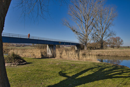 Seitenansicht der blauen Stahlbr&uuml;cke Weisch&uuml;tz &uuml;ber die Unstrut mit Uferlandschaft und Schilfbewuchs im sonnigen Wetter, Weisch&uuml;tz bei Laucha an der Unstrut, Burgenlandkreis, Sachsen-Anhalt, Deutschla