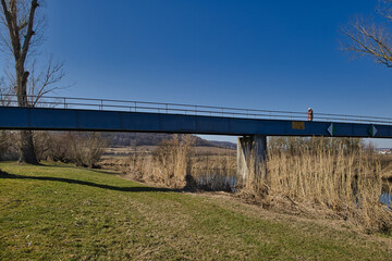 Seitenansicht der blauen Stahlbr&uuml;cke Weisch&uuml;tz &uuml;ber die Unstrut mit Uferlandschaft und Schilfbewuchs im sonnigen Wetter, Weisch&uuml;tz bei Laucha an der Unstrut, Burgenlandkreis, Sachsen-Anhalt, Deutschla