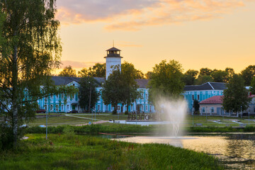 Vyshny Volochyok, Tver region, Russia. Evening urban landscape. The magistrate's building with a fire tower. A fountain on the Tsna River. On the embankment there is a text in Russian "My Volochyok".