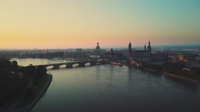 A aerial drone shot gliding from afar toward the historic city center of Dresden, captured at dawn above the River Laube
