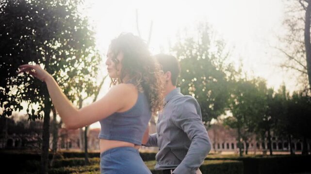 Romantic couple dancing bachata in a park at sunset