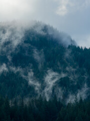Fototapeta premium Misty Forest Mountain Range Shrouded in Clouds Above Howe Sound, BC, A Serene Alpine Landscape