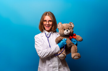 Portrait of a pediatrician with a teddy bear. The cheerful and smiling pediatrician holding a plush toy in her hand