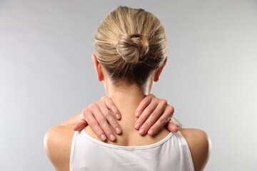 Obraz premium Woman doing neck massage on light grey background, back view