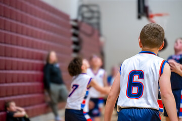 Fototapeta premium Kids play basketball in a gym during an afternoon practice session in a youth sports program
