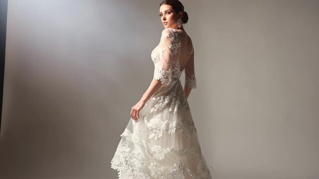 Medium shot of a bride in a layered lace overlay gown showcasing intricate handsewn floral patterns and delicate scalloped edges under soft lighting.