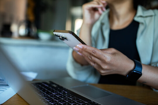 Person using smartphone and laptop at home office
