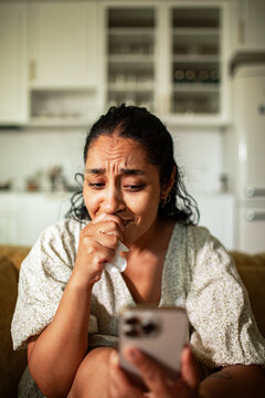 Worried woman reading bad news on phone at home