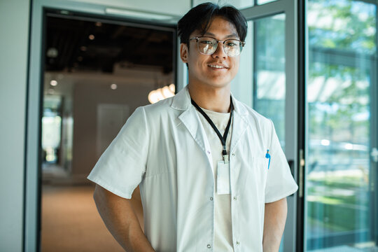Smiling healthcare worker in lab coat at modern clinic corridor