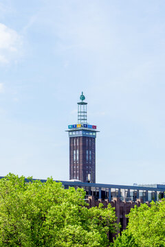 Cologne, Germany - May 12, 2024: Historic Messeturm Skyscraper and RTL Tower with Lush Green Trees and Blue Sky
