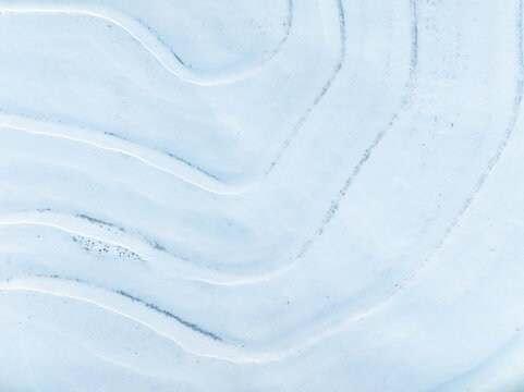 Aerial top down view of patterns of snow drifts in field
