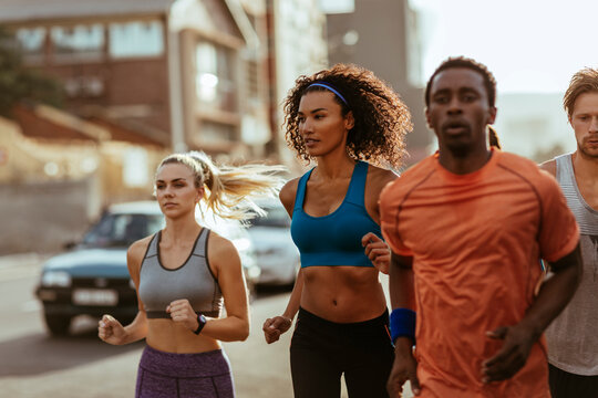 Group of young adults running on city street