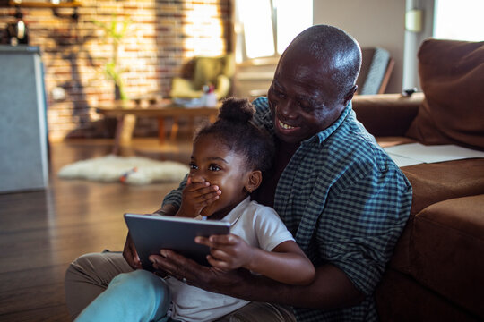 Grandfather and granddaughter using tablet at home
