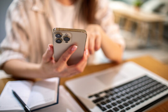 Person using smartphone while working at home office desk
