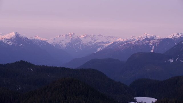 Snow-capped mountains at dusk with purple sky