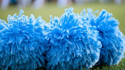 Close-up of vibrant blue cheerleader pom-poms on green grass field, a celebration of team spirit and athletic support